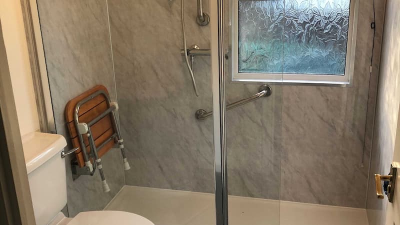 Walk in shower with slide door and light grey walls
