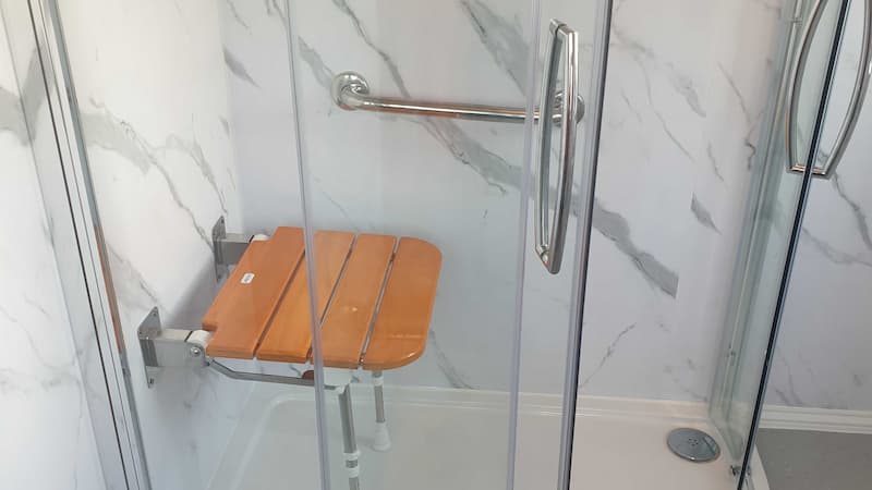 Walk in light grey shower with handrails and seat