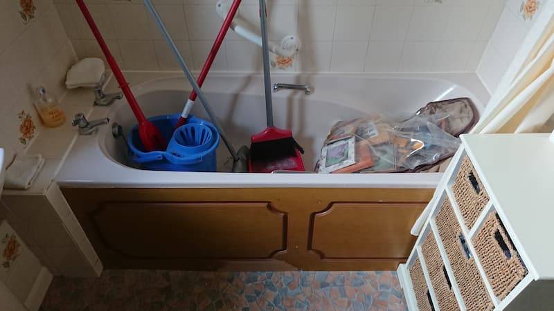 small bathtub filled with mops and brooms