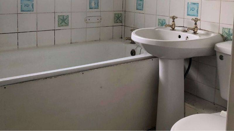 Dirty bathroom with sink toilet and bath